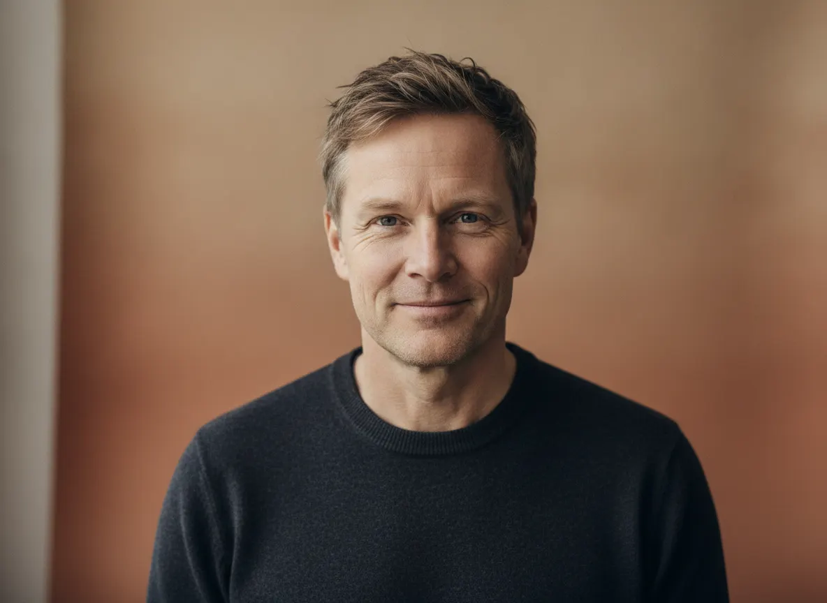 Smilende skandinavisk gründer i mørk genser i et lunt studio