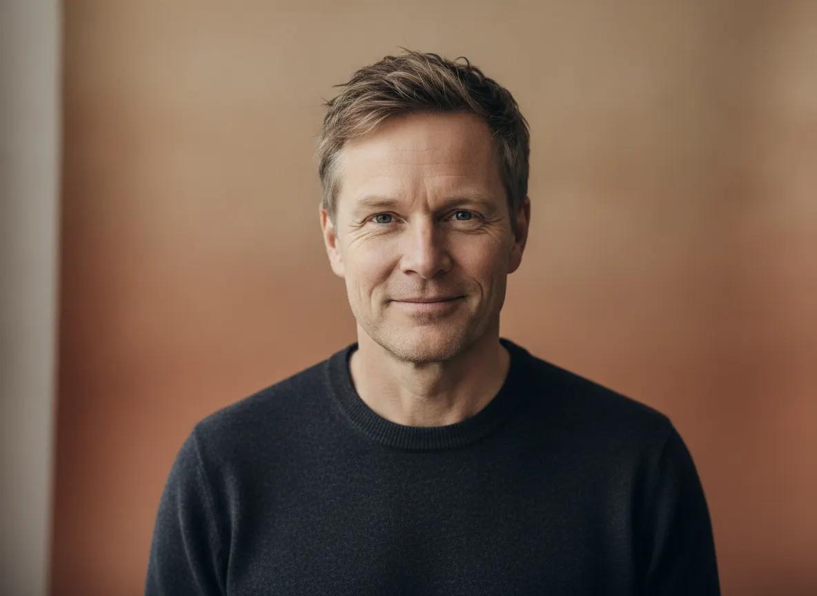 Smilende skandinavisk gründer i mørk genser i et lunt studio